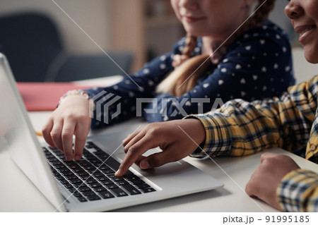 Close-up of two kids typing together on laptop during online studying sitting at table 91995185