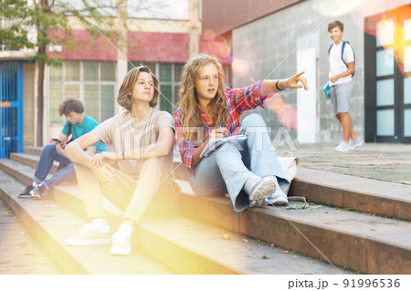 Teenagers sitting on stairs beside school Teenagers sitting on stairs beside school 91996536