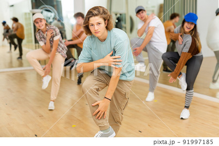 Teenage boy practicing hip-hop movements with group in studio 91997185