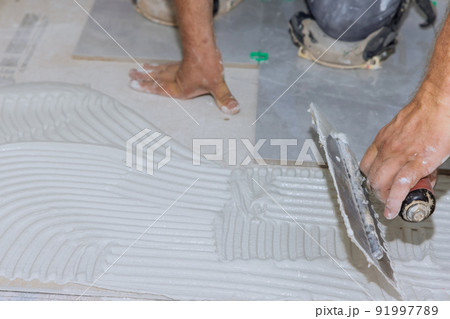Adding wet mortar to the bathroom floor before applying tiles puts adhesive on the tiles Adding wet mortar to the bathroom floor before applying tiles puts adhesive on the tiles 91997789