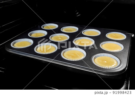 Uncooked homemade cupcakes, muffins in electric oven, black background 91998423