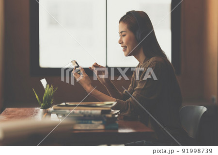 Young composer woman recording music lyrics her voice in to smartphone. 91998739