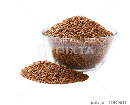 raw buckwheat in a glass plate and scattered isolated on white background. 91999011