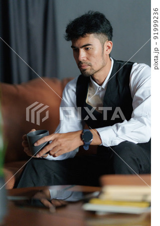 Portrait of Asian Businessman with cup of coffee and sitting at cozy sofa. 91999236