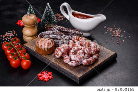 Delicious dry sausage with walnuts on a christmas table. Dry cured fuet sausage on a dark background Delicious dry sausage with walnuts on a christmas table. Dry cured fuet sausage on a dark background 92000169