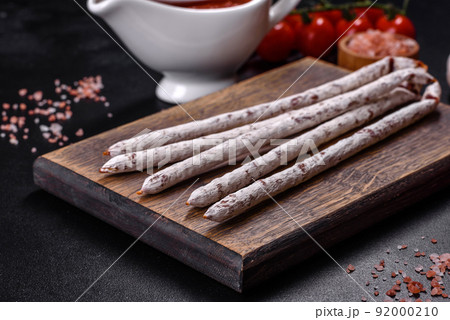 Delicious dry sausage with walnuts on a concrete table. Dry cured fuet sausage on a dark background 92000210
