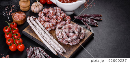Delicious dry sausage with walnuts on a concrete table. Dry cured fuet sausage on a dark background 92000227
