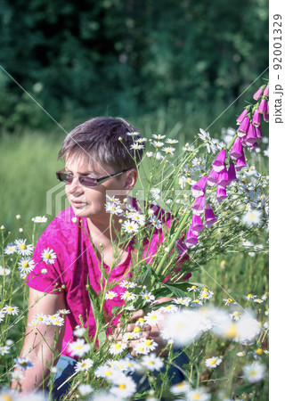 Woman collects a bouquet of wild flowers with daisies and foxglove Woman collects a bouquet of wild flowers with daisies and foxglove 92001329
