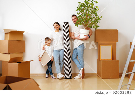 Portrait of happy family with cardboard boxes in new house at moving day 92003298