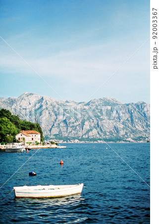 Moored fishing boat on the background of the coast of Perast Moored fishing boat on the background of the coast of Perast 92003367