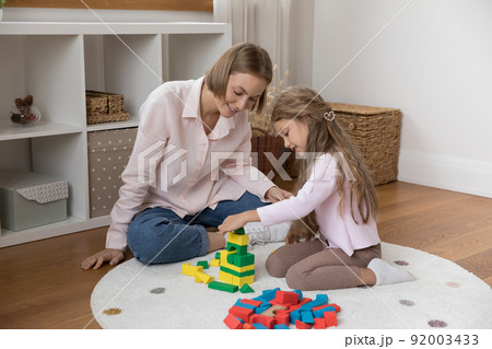 Happy mom and little daughter kid playing on warm floor Happy mom and little daughter kid playing on warm floor 92003433