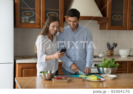 Couple using cellphone making food order while cooking lunch 92004170