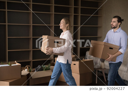 Satisfied couple carrying paper cardboard boxes in living room Satisfied couple carrying paper cardboard boxes in living room 92004227