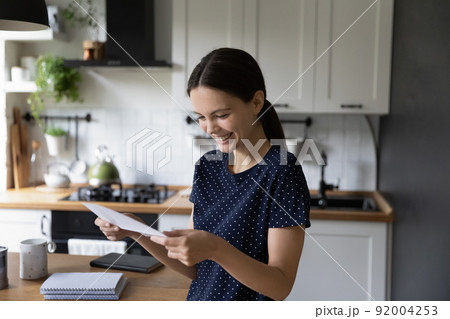 Cheerful happy student girl reading document, receiving letter from college 92004253