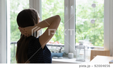 Dreamy young woman sitting at home table, looking at window 92004656