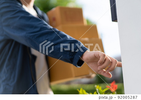 Asian postman with a hygiene protective face mask picking up a parcel package or parcel box from the truck for deliver to customer's door. New Normal concept during covid-19 or coronavirus pandemic 92005287