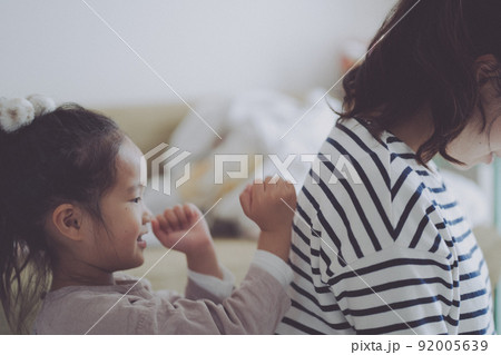 楽しそうにママに肩叩きをする女の子 楽しそうにママに肩叩きをする女の子 92005639