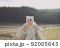 夕焼けに子どもを抱っこして楽し 92005643