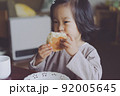家でパンを頬張る女の子 92005645