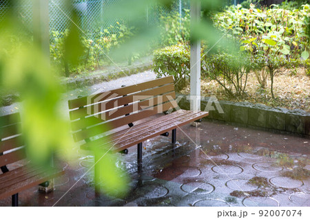 緑を前ボケで入れた雨の日の公園のベンチ 92007074
