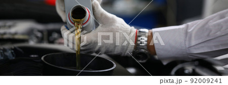 Worker refueling and pouring new oil into engine motor car 92009241