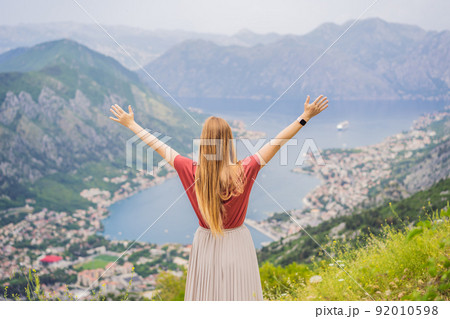 Woman tourist enjoys the view of Kotor. Montenegro. Bay of Kotor, Gulf of Kotor, Boka Kotorska and walled old city. Travel to Montenegro concept. Fortifications of Kotor is on UNESCO World Heritage 92010598