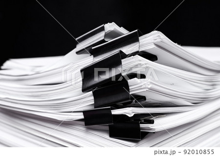 A stack of office papers, some of which are fastened with black binders A stack of office papers, some of which are fastened with black binders 92010855
