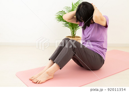 室内で腹筋をするミドル女性 92011354
