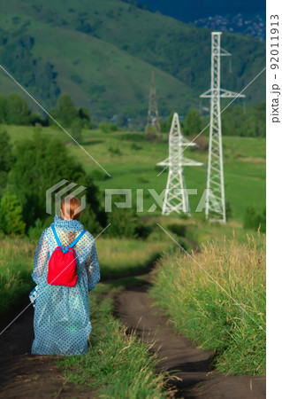 rear view, a red haired girl, a child, a teenager walks along a field road 92011913