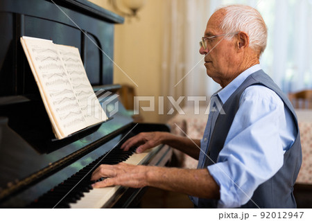 Senior man learning to play piano 92012947