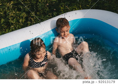 Happy children lie in the pool and splash with their feet Happy children lie in the pool and splash with their feet 92013179
