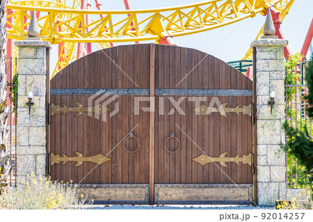 Wooden fabulous rounded gates in medieval style in an amusement park on a sunny day. 92014257