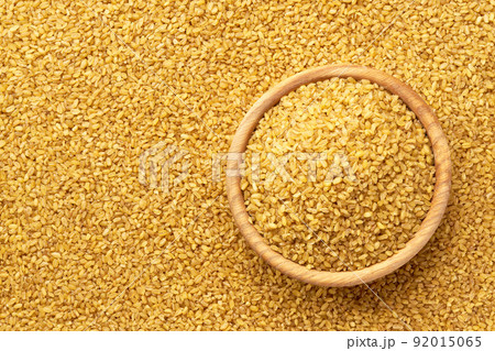 wooden plate with raw bulgur on a bulgur background close-up top view. 92015065