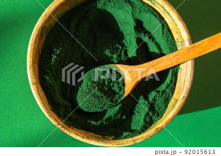 Blue-green algae Chlorella and spirulina powder in bamboo eco bowl. Super powder in spoon. Detox superfood. Natural supplement of algae Blue-green algae Chlorella and spirulina powder in bamboo eco bowl. Super powder in spoon. Detox superfood. Natural supplement of algae 92015613