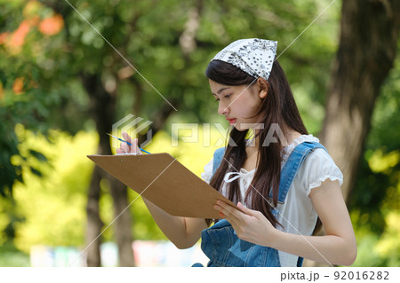 Young asian woman pianting and relaxing in park. Young asian woman pianting and relaxing in park. 92016282
