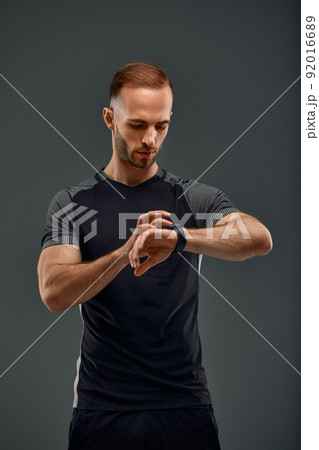 Sportsman checking heart rate on fitness tracker when training studio shot on gray background 92016689