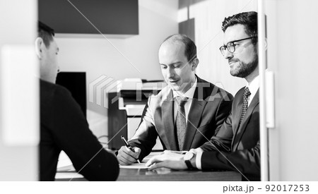 Group of confident successful business people reviewing and signing a contract to seal the deal at business meeting in modern corporate office. Group of confident successful business people reviewing and signing a contract to seal the deal at business meeting in modern corporate office. 92017253