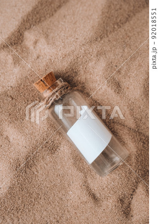 Letter in a bottle on the beach. Island lifestyle. Paper Message in a glass bottle with a cork on the sand. Note on salvation, please help. SOS concept. Copy space 92018551