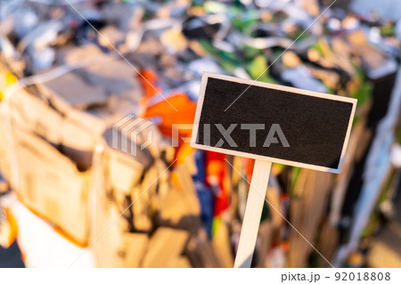 Wooden information label sign with black chalkboard against defocused Paper pressed bales at the modern waste hazardous processing plant. Mockup template copy space Separate garbage collection. Wooden information label sign with black chalkboard against defocused Paper pressed bales at the modern waste hazardous processing plant. Mockup template copy space Separate garbage collection. 92018808