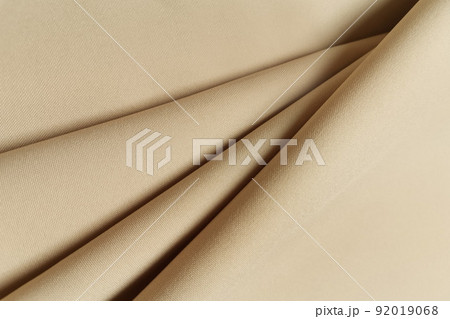 Beige crumpled or wavy fabric texture background. Abstract linen cloth soft waves. Gabardine wool fabric. Merino yarn. Smooth elegant luxury cloth texture. Concept for banner or advertisement. 92019068
