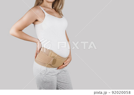 Pregnant woman belly in prenatal pregnancy maternity belt. Orthopedic abdominal support waist, back, abdomen band. Belly brace or band for pregnancy. Horizontal web banner. Torso of pregnant model. 92020058