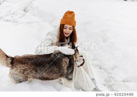 young woman in the snow playing with a dog fun friendship winter holidays 92020490