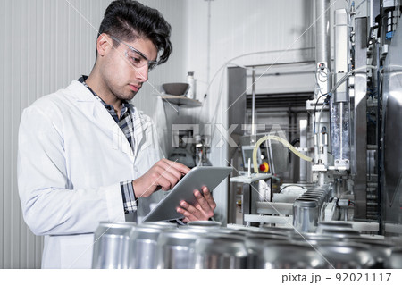 Factory worker inspecting production line on beverage factory with computer tablet. Factory worker inspecting production line on beverage factory with computer tablet. 92021117