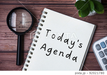 Today's agenda text on notepad. Magnifying glass and calculator background. Today's agenda text on notepad. Magnifying glass and calculator background. 92021780