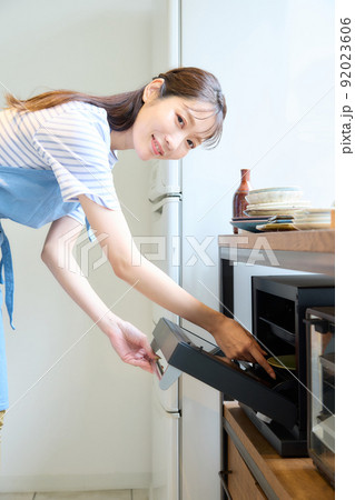 オーブンレンジで料理をする女性 92023606