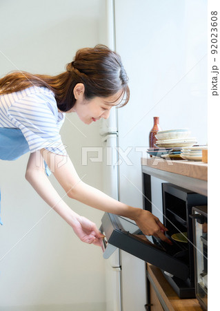 オーブンレンジで料理をする女性 92023608