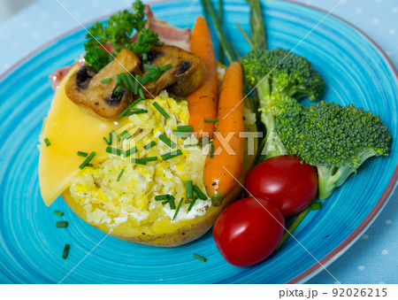 Baked potatoes with bacon, cheese, champignons, vegetables Baked potatoes with bacon, cheese, champignons, vegetables 92026215