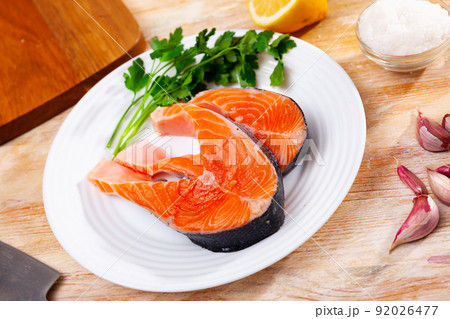 Raw salmon steaks with lemon, parsley, garlic Raw salmon steaks with lemon, parsley, garlic 92026477