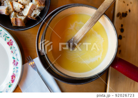 Fondue Savoyarde heating in caquelon on table Fondue Savoyarde heating in caquelon on table 92026723