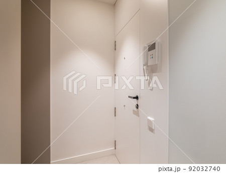 Entrance hall area in modern refurbished apartment. White walls and door with intercom system. Entrance hall area in modern refurbished apartment. White walls and door with intercom system. 92032740